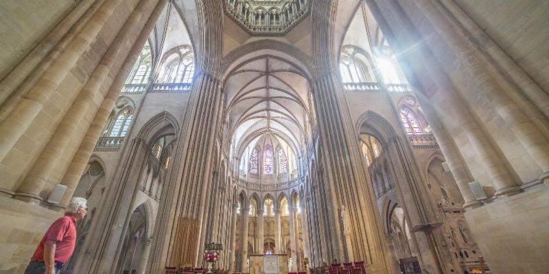 Des touristes admirant l’intérieur d’une cathédrale française, capturant des photos de l’architecture et des vitraux.